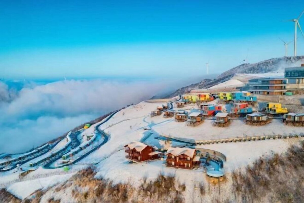 Ein schneebedecktes Dorf mit bunten Häusern und einer kurvenreichen Straße.