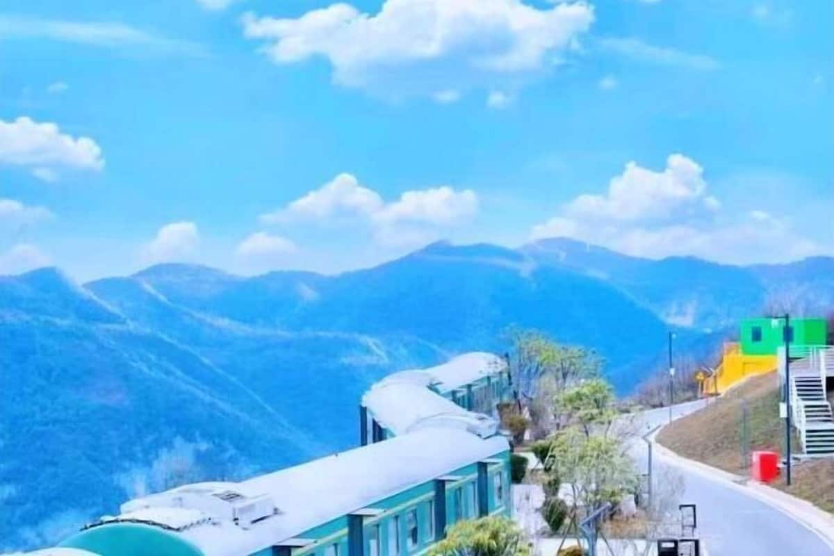 A train on a mountain track with a view of the mountains in the background.