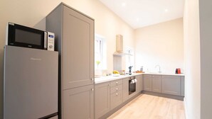 A modern kitchen with grey cabinetry, a built-in microwave, and a window providing natural light.