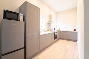 A modern kitchen with grey cabinetry, a built-in microwave, and a window providing natural light.