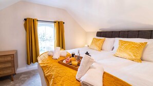 A hotel room with a bed, a wooden nightstand, a window with curtains, and a tray with breakfast items.