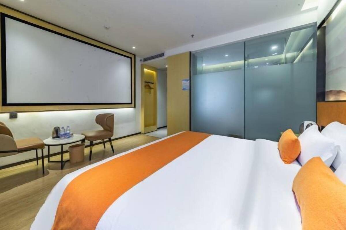 Une chambre d’hôtel avec un lit, un bureau, une chaise et une grande fenêtre.