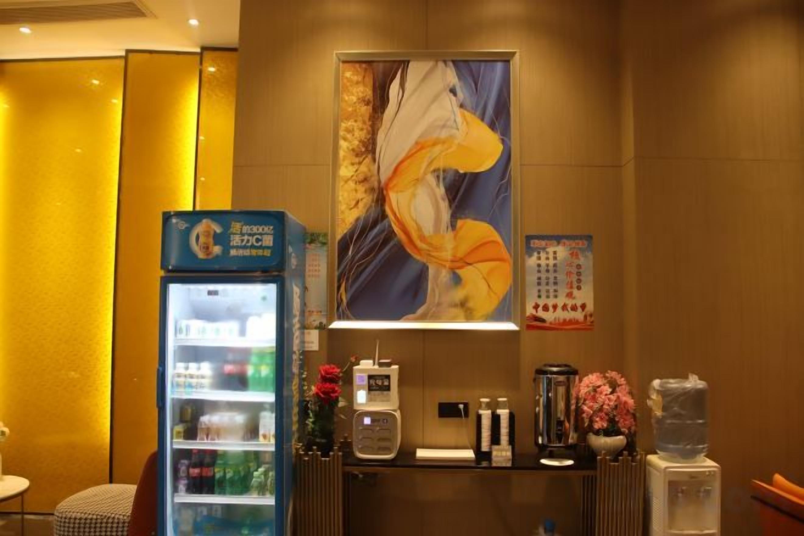 Una zona reception con distributore automatico di bevande, macchina del caffè, distributore d'acqua e un'elegante composizione floreale.