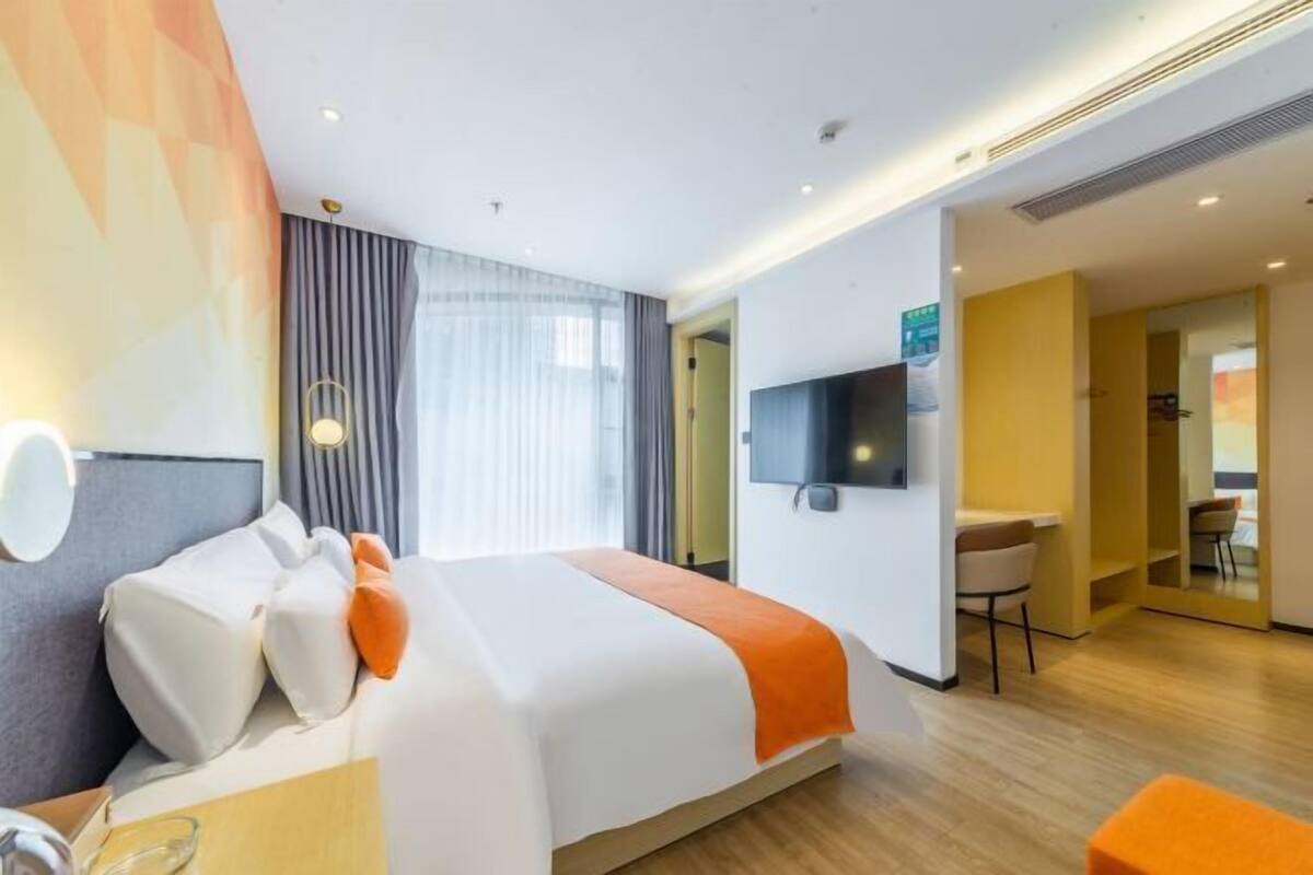 Une chambre d’hôtel moderne équipée d’un lit, d’un bureau et d’une télévision.