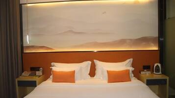 A hotel room with a large bed, two nightstands, a wall-mounted telephone, and a nightstand with a coffee maker.