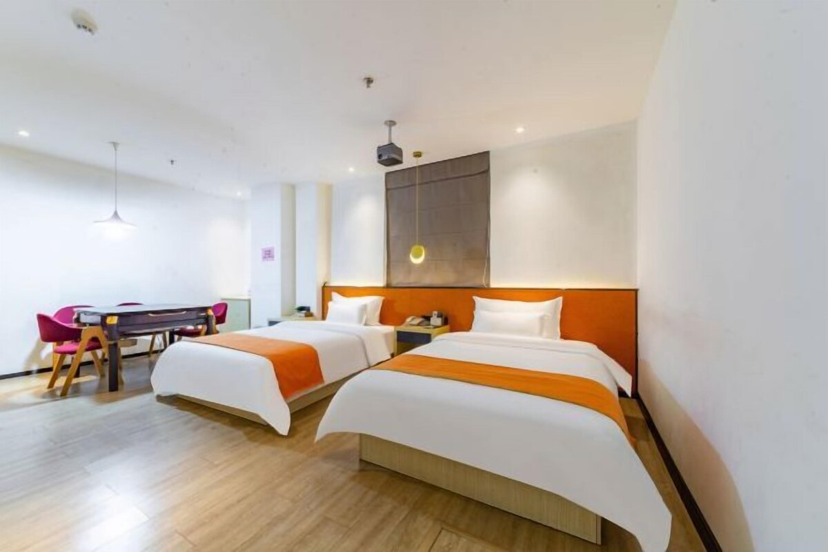 Une chambre d’hôtel avec deux lits, un bureau avec des chaises et une grande fenêtre.