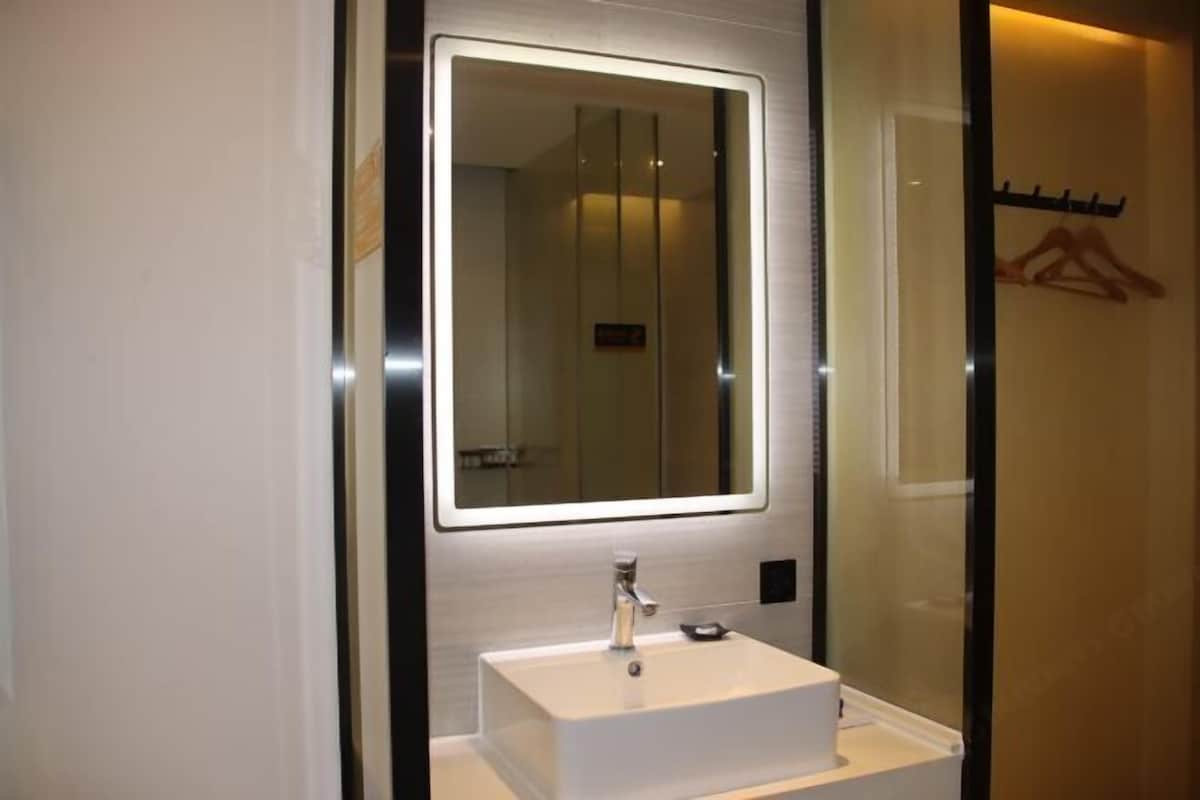A modern bathroom with a large mirror, a white sink, and a towel rack.