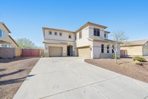 Two-story house with a garage and covered driveway, set amidst a beautifully landscaped yard.