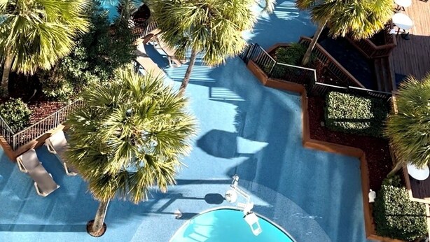 Vista aérea de un resort con varias piscinas rodeadas de palmeras y zonas de descanso.