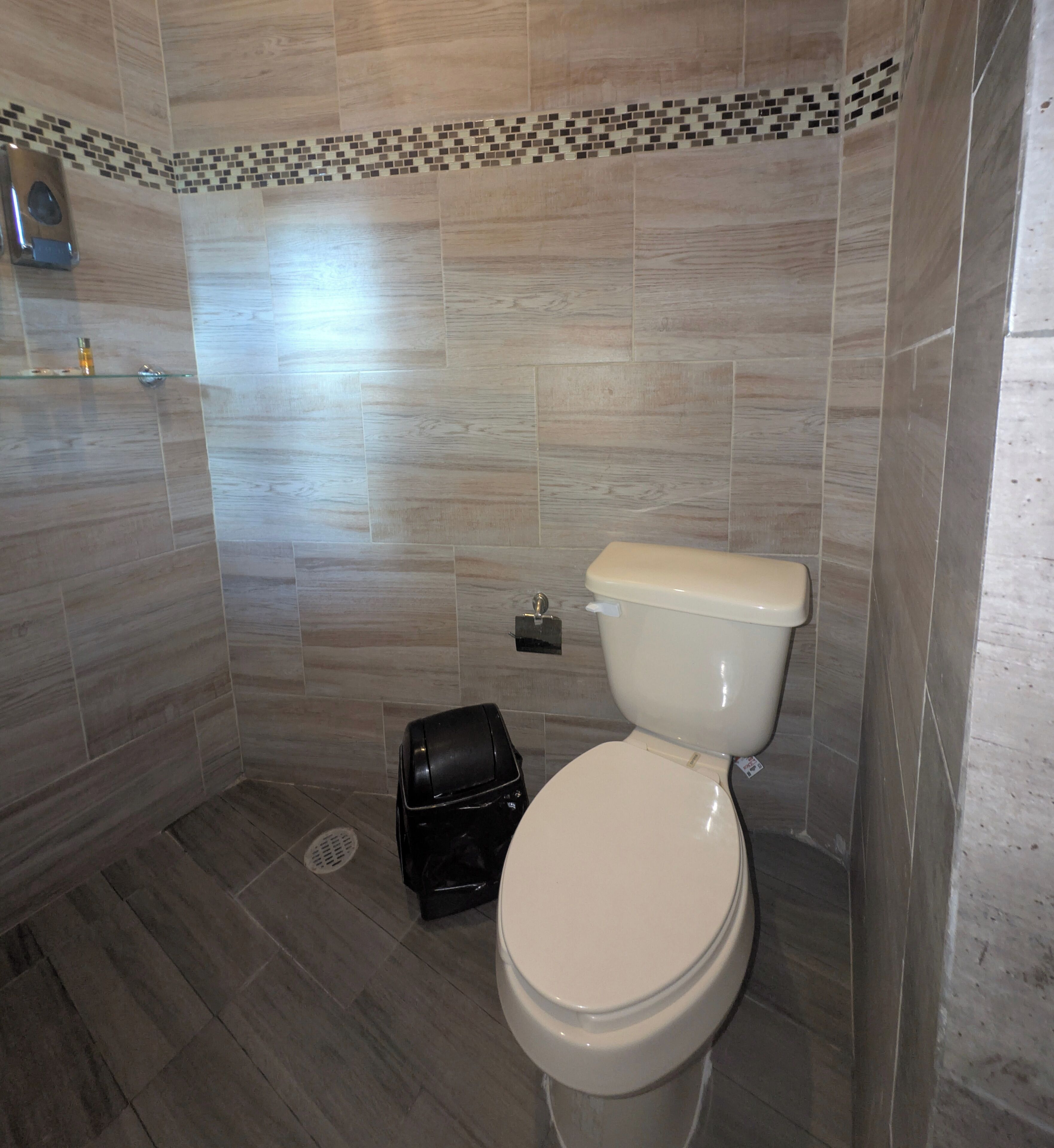 Un baño moderno con inodoro, un cubo de basura y zona de ducha.