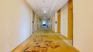 A long, narrow hotel corridor with doors on both sides, a patterned carpet, and a ceiling with recessed lighting. - Vienna International Hotel (Zhongshan Torch Development Zone (Zhongshan)