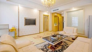 A spacious living room with a chandelier, a flat-screen TV, a coffee table, and a sofa. - Vienna International Hotel (Zhongshan Torch Development Zone (Zhongshan)