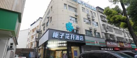 A building with a sign for "Kongzi Flower Hotel" and a 7-Eleven store.