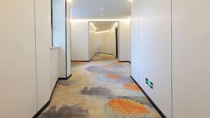 Ein Hotelgang mit Teppichboden und weißen Wänden.