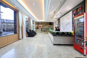 Un hall de hotel con mostrador de recepción, zona de estar y máquina expendedora.