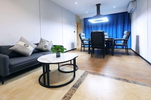 A modern living room with a sofa, a round table, and a dining area with chairs. - Zhi Xin Zhi Zi Hua Kai Hotel (Xiantao Bus Station Hongda Road Branch) (Xiantao)