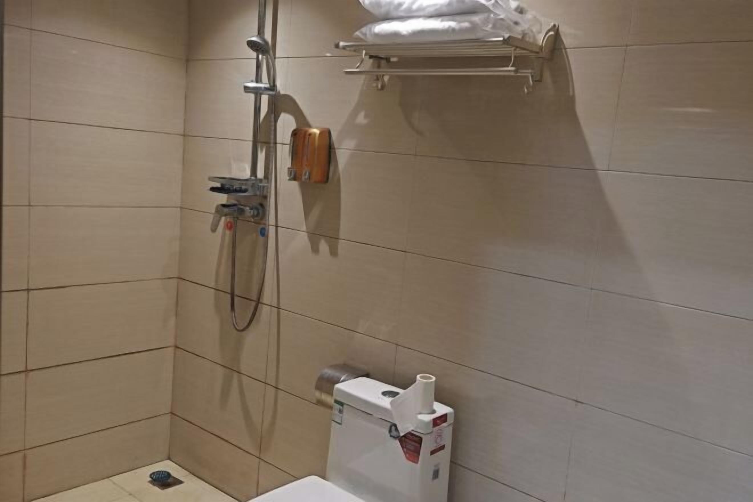 Ein kleines Badezimmer mit Fliesen, einer Dusche, einer Toilette und einem Handtuchhalter.