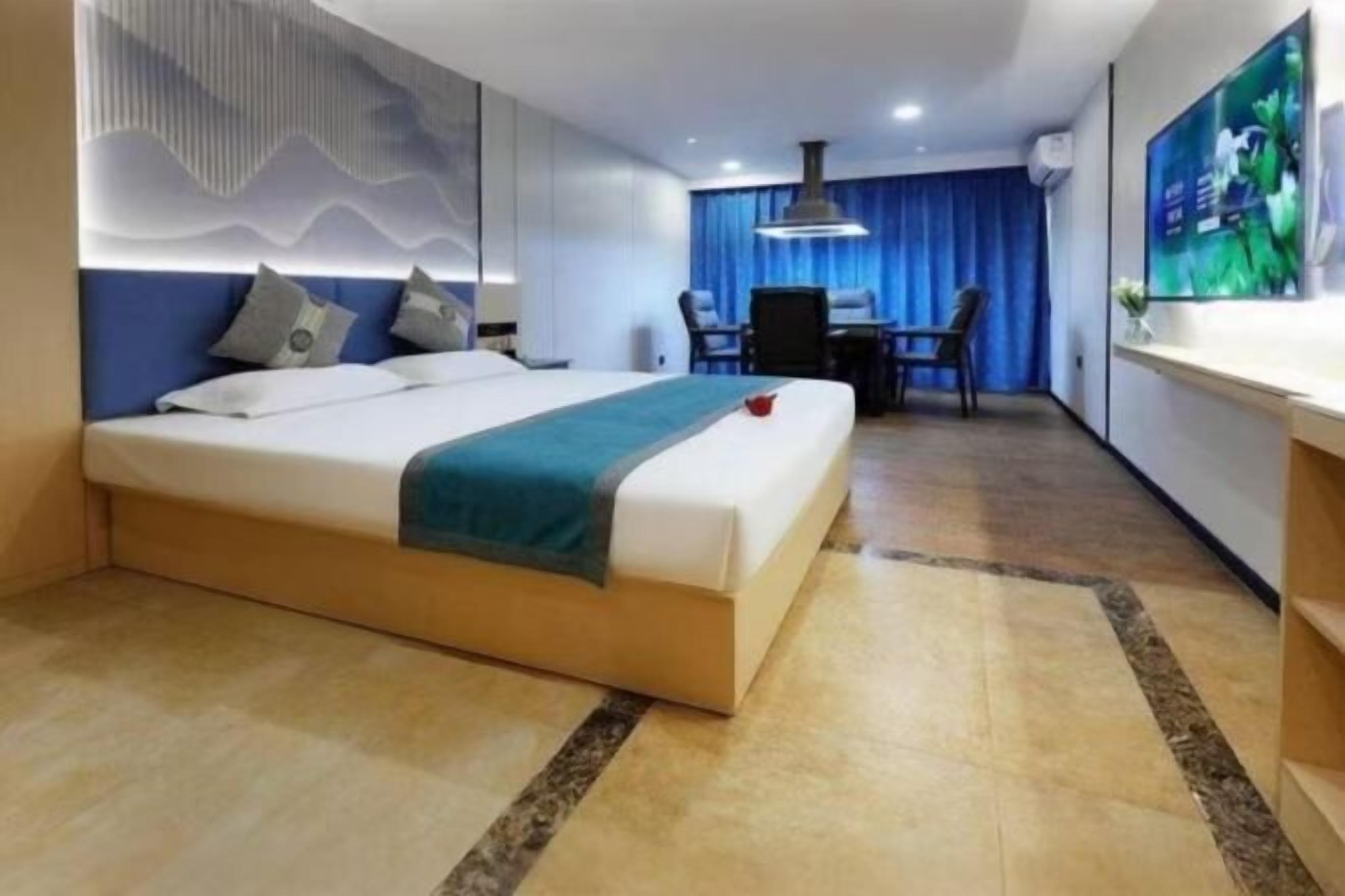 A modern hotel room with a large bed, a desk, and a television.