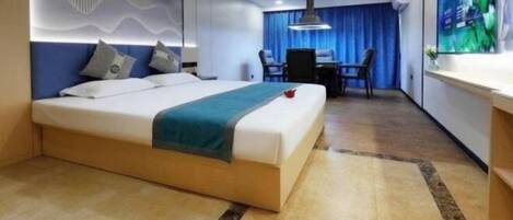 A modern hotel room with a large bed, a desk, and a television.