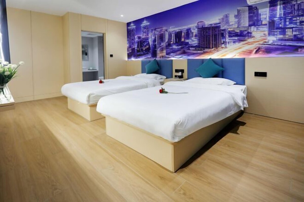 A hotel room with two beds, a cityscape mural on the wall, and a wooden floor.