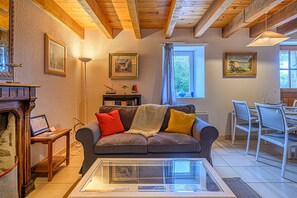 A cozy living room with a sofa, a glass coffee table, a fireplace, and a dining area with a table and chairs.