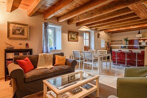 A cozy living room with a sofa, a glass coffee table, and a dining area with a white table and chairs.