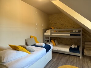 Une chambre de dortoir avec des lits superposés, un lit simple et une petite fenêtre.