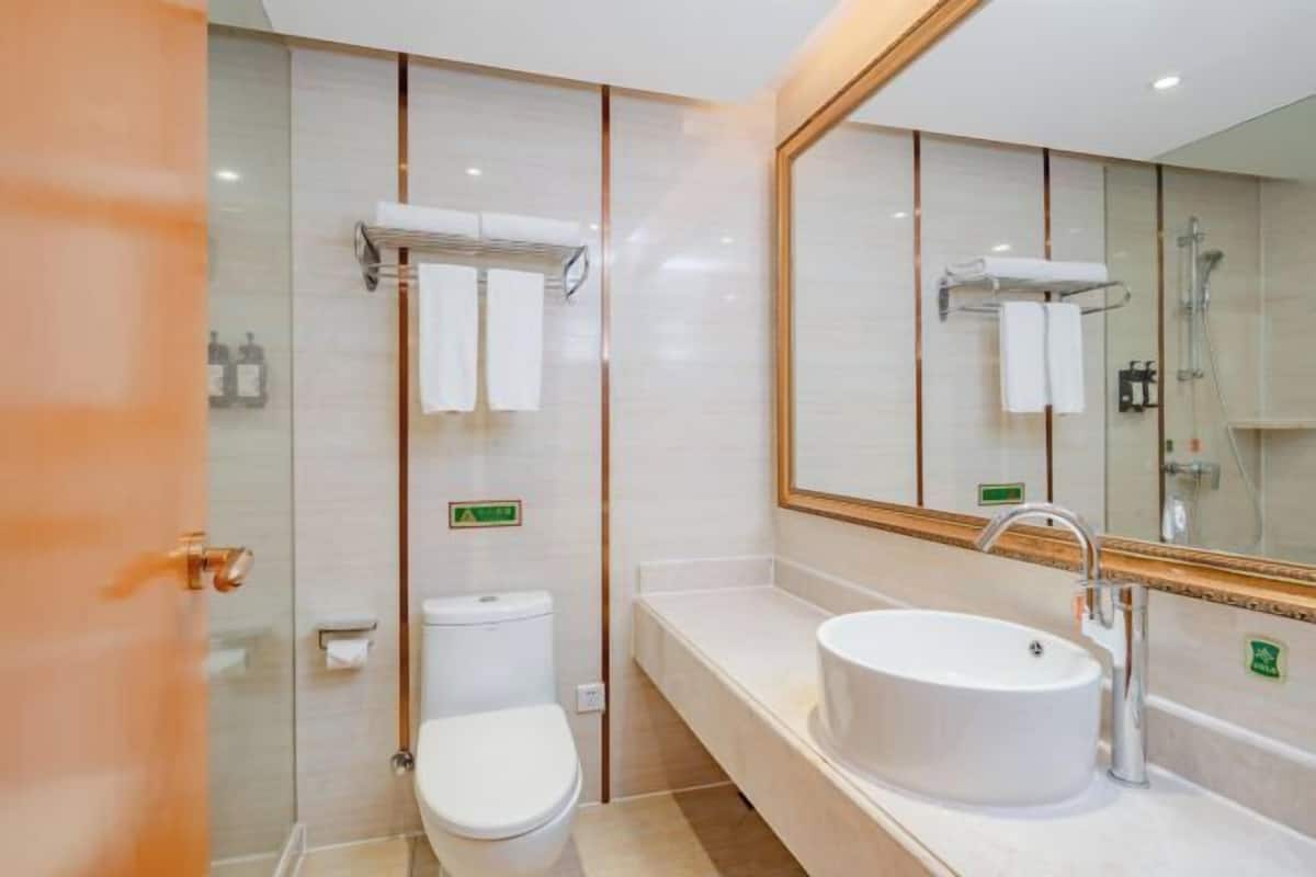 A modern bathroom with a toilet, sink, and shower. There are towels and toiletries visible.