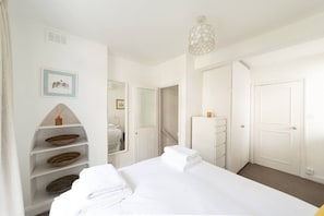 Ein Hotelzimmer mit einem Bett, einem Kleiderschrank, einem Spiegel, einer Ablagefläche mit Körben und einer Pendelleuchte.
