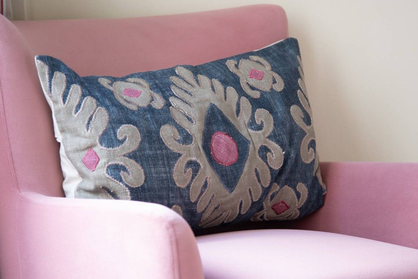 A chair with a decorative pillow featuring a floral pattern.