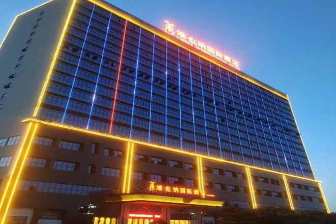 Un edificio de hotel de varios pisos con señalización iluminada y una entrada destacada.