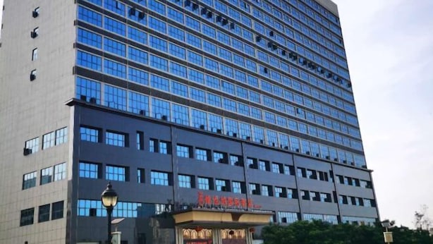 A multi-story hotel with a modern facade, featuring a prominent entrance with a sign. - Vienna International Hotel (Dushan) (Dushan)