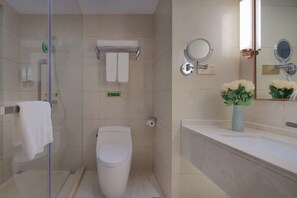 Ein modernes Badezimmer mit Duschkabine aus Glas, Toilette, Waschbecken mit Blumenvase und Spiegel mit zwei runden Spiegeln.