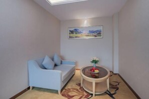 Ein Zimmer mit einem hellblauen Sofa, einem runden Tisch mit Blumenvase und einem Bild an der Wand.