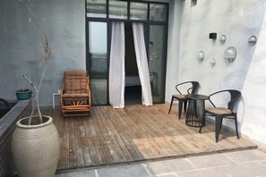 A wooden deck with a wicker chair, a table, and a large vase. - Yiru Hotel (Xinfeng) (Xinfeng)
