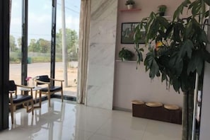 Un hall de hotel con zona de estar, mostrador de recepción y un amplio ventanal con vistas al exterior.