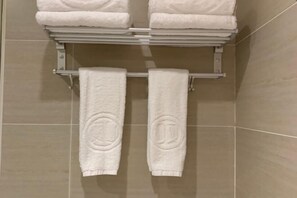 A bathroom with a towel rack holding two folded white towels and two hanging towels with circular patterns. - Yiru Hotel (Xinfeng) (Xinfeng)