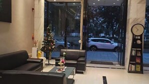 A modern lobby with leather sofas, a Christmas tree, and a clock on the wall. - Yiru Hotel (Xinfeng) (Xinfeng)