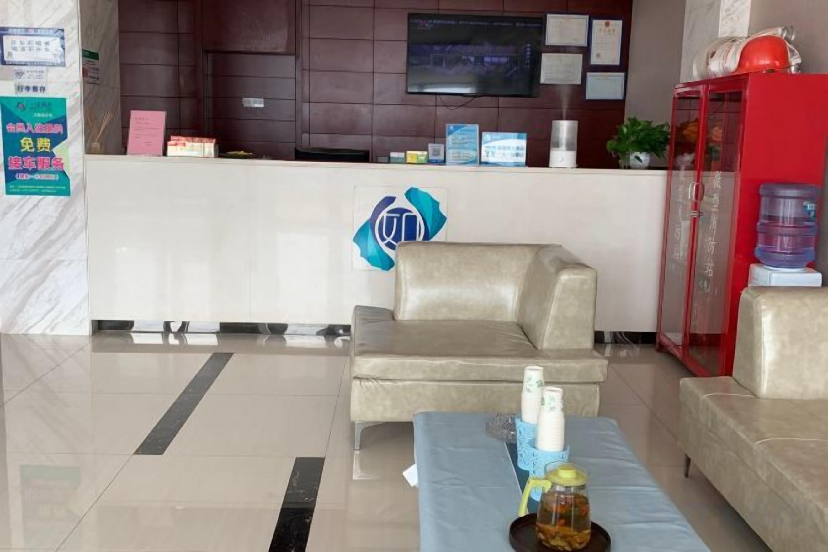 A reception area with a reception desk, a sofa, a coffee table with items, and a red cabinet.
