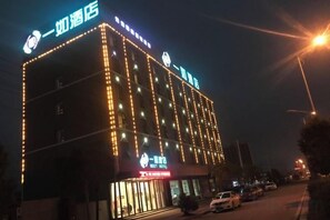 A multi-story hotel with illuminated signage and a prominent entrance. - Yiru Hotel (Xinfeng) (Xinfeng)