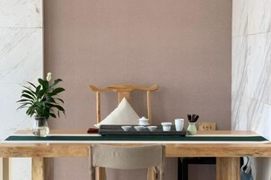 A wooden table with a green mat, a chair, a potted plant, a wooden chair, and a small table with cups and a teapot.