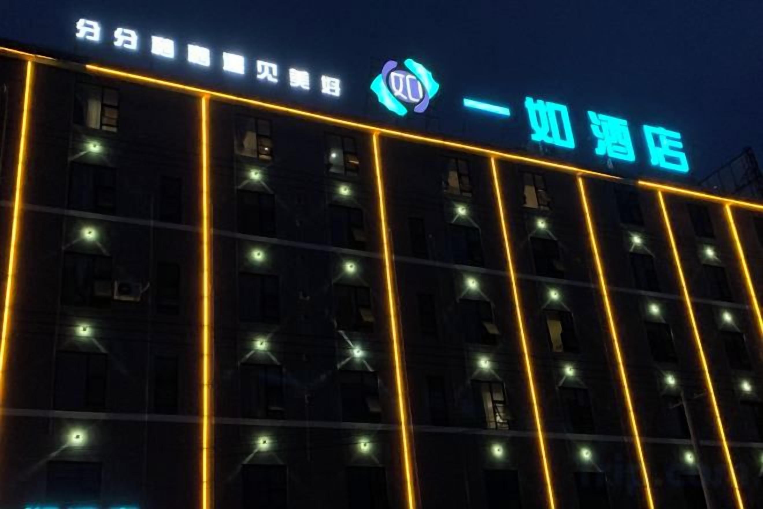 A building facade with illuminated windows and a neon sign.