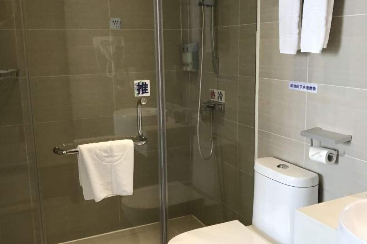 A modern bathroom with a glass shower enclosure, a white toilet, and a sink area.