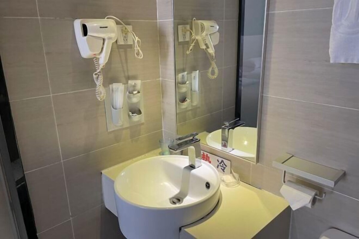 A bathroom with a sink, mirror, hairdryer, and towel rack.