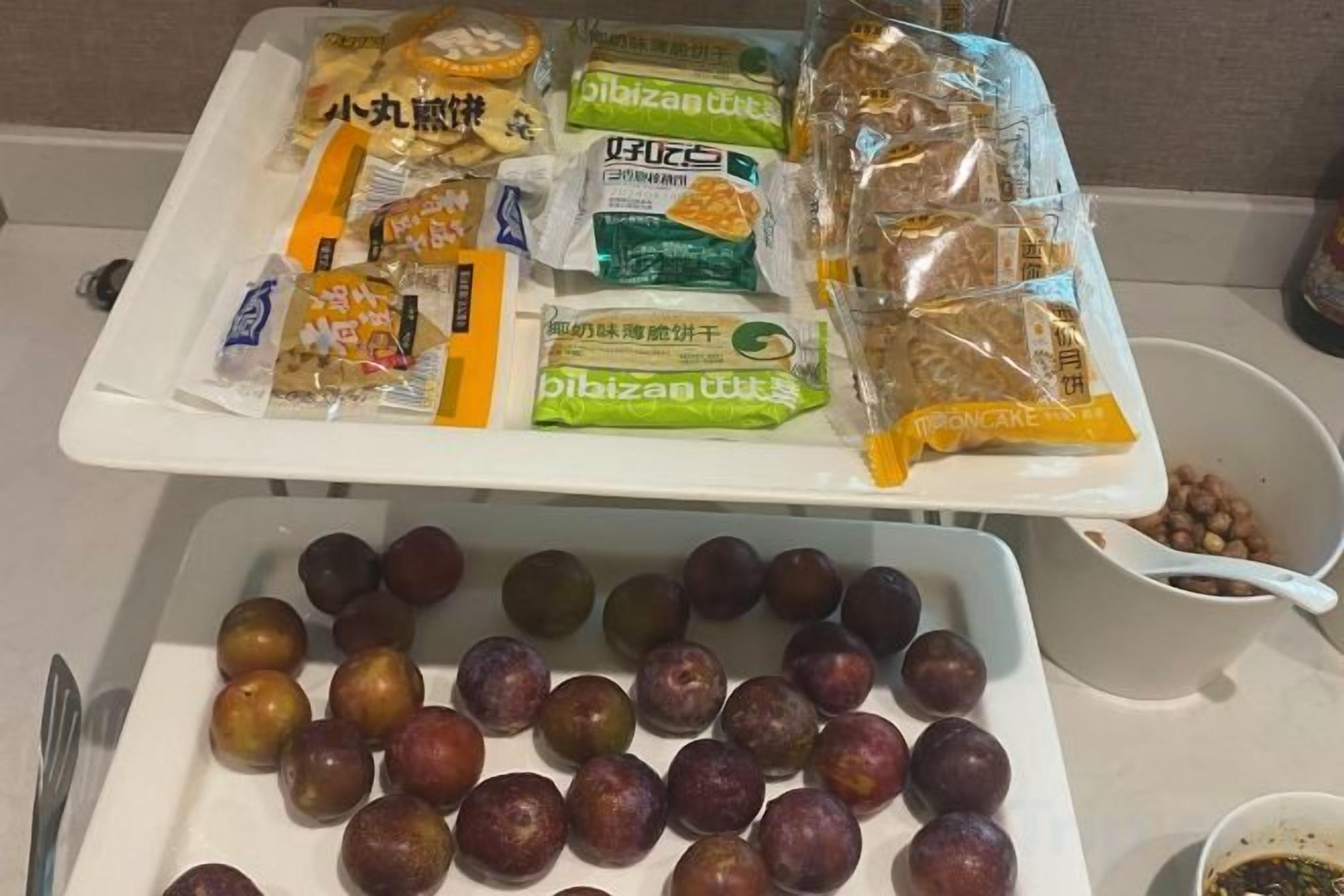 A tray with snacks and fruits on a table.
