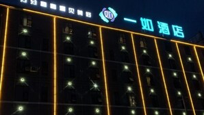 A hotel facade with illuminated signage and vertical light strips. - Yiru Hotel (Xinfeng) (Xinfeng)