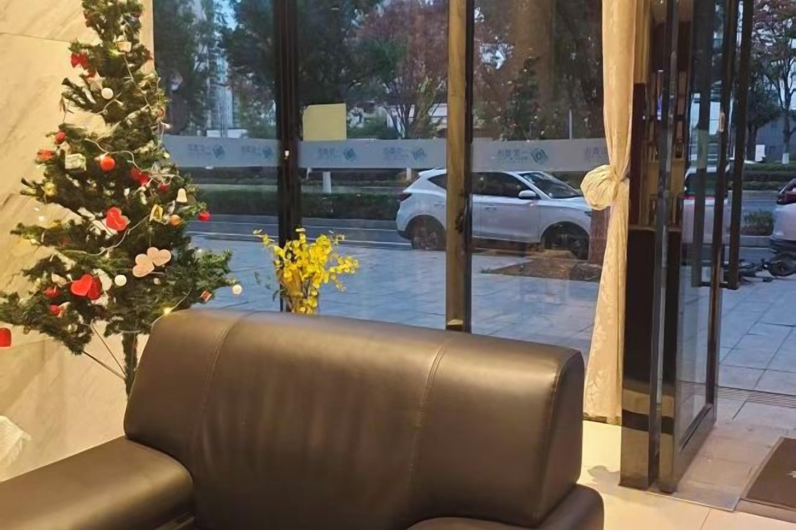 A leather chair in a room with a view of a parking lot and a Christmas tree.