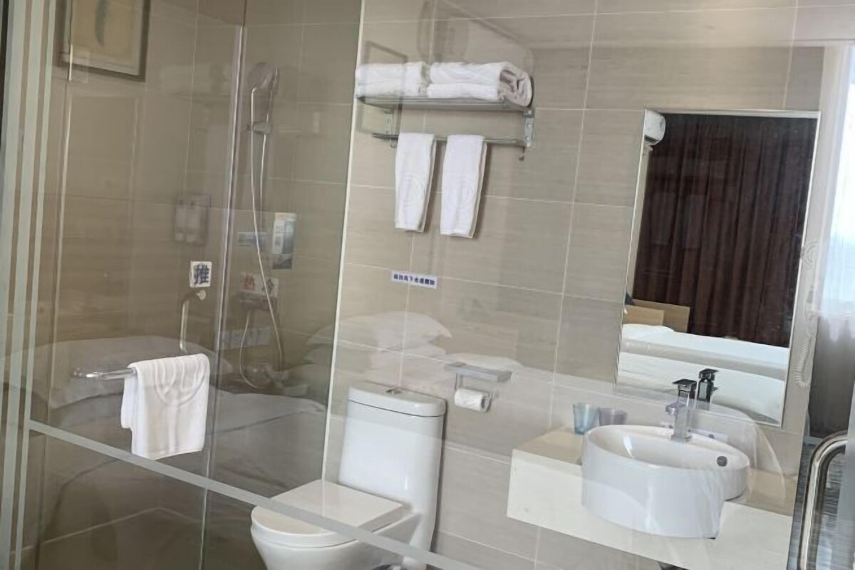 A modern bathroom with a glass shower enclosure, a toilet, a sink, and a towel rack.