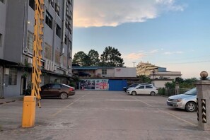 A parking lot with several cars, a yellow ladder, and buildings in the background. - Yiru Hotel (Xinfeng) (Xinfeng)