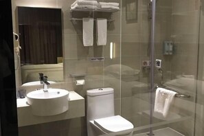 A modern bathroom with a round sink, toilet, and glass-enclosed shower. - Yiru Hotel (Xinfeng) (Xinfeng)